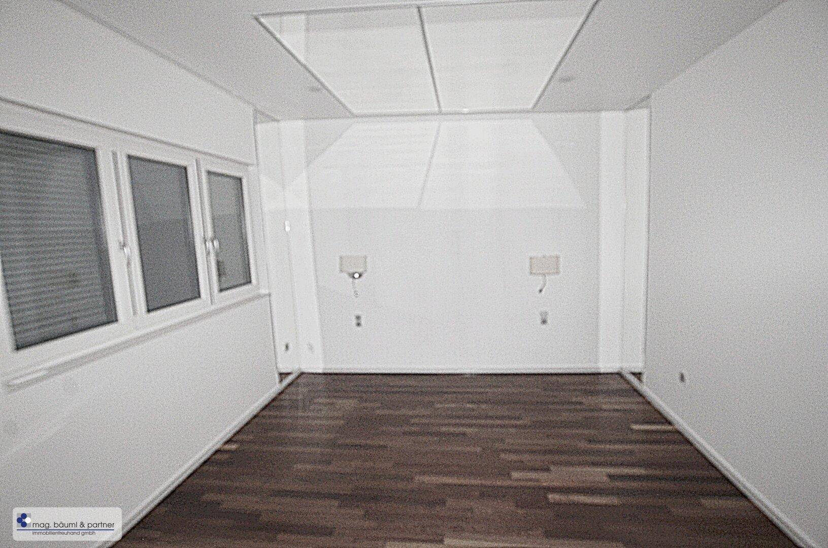 Geräumiges Schlafzimmer mit dunklem Holzboden, Fenster und integrierter Deckenbeleuchtung.