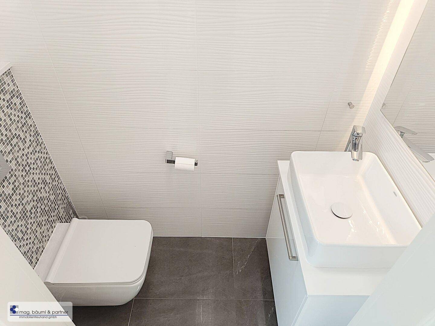 Modernes Gäste-WC mit wandhängender Toilette und stilvollem Waschbecken.