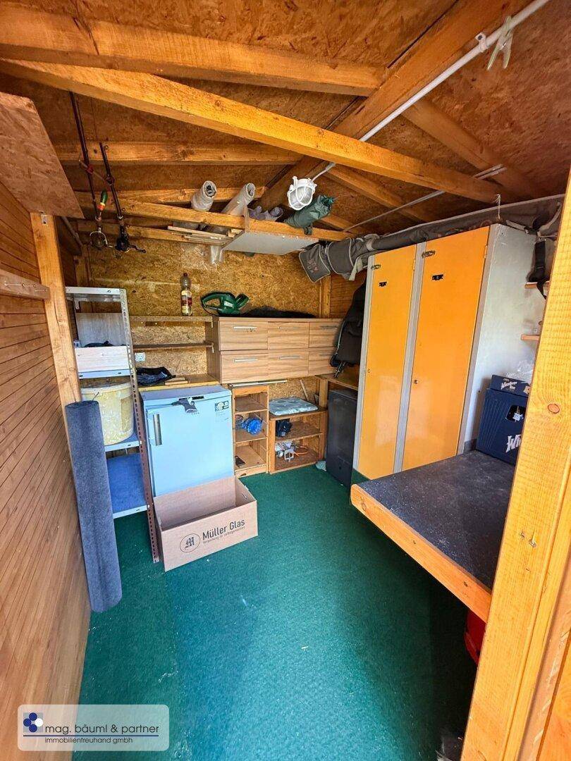 Praktischer Geräteschuppen mit Holzverkleidung, Regalen und Stauraum für Gartengeräte und Vorräte.
