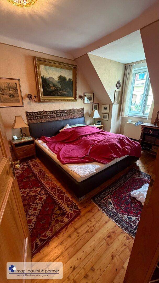 Gemütliches Schlafzimmer mit Holzboden, Dachschräge und traditioneller Einrichtung.