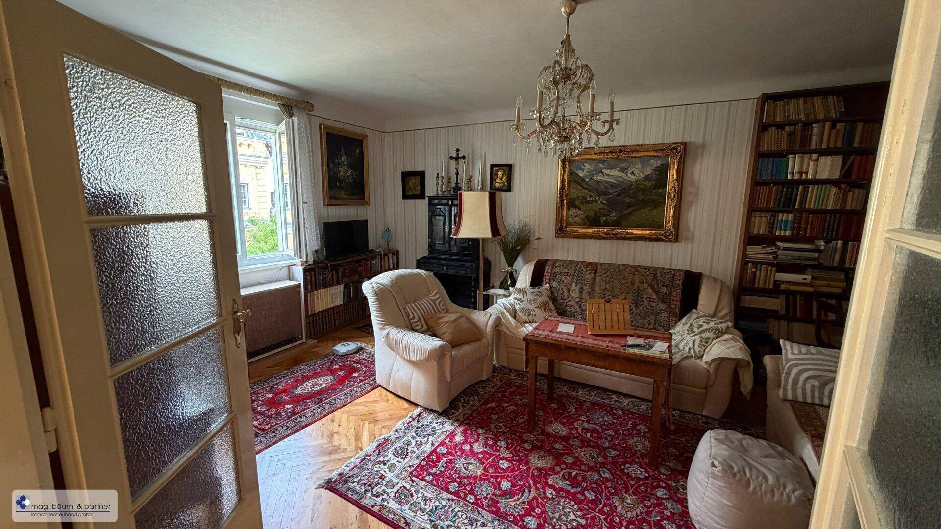 Helles Wohnzimmer mit bequemen Sofas, Parkettboden und Blick ins Grüne.