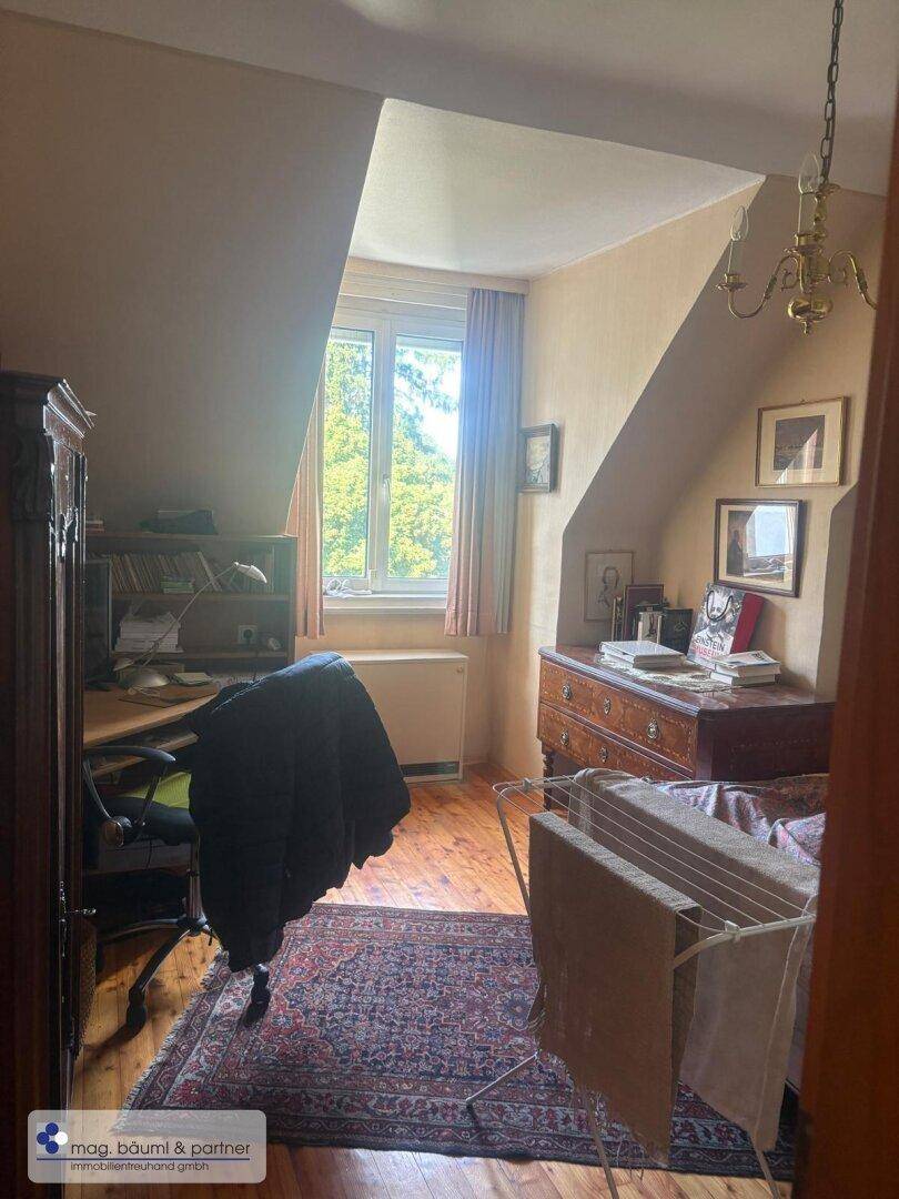 Arbeitszimmer mit Dachschräge, Holzboden und Blick ins Grüne.