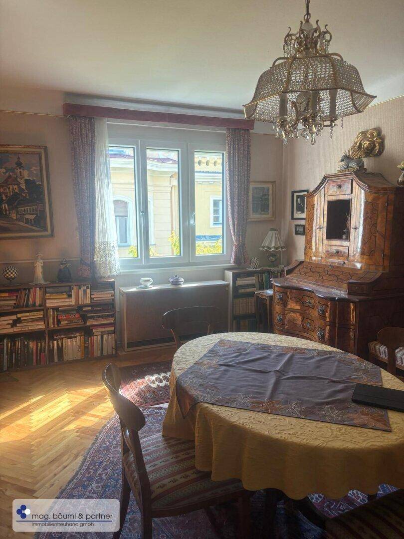 Helles Esszimmer mit Kronleuchter, antiken Möbeln und Blick auf die umliegenden Gebäude.