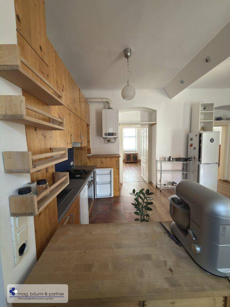 Funktionale Küche mit Holzschränken, Arbeitsplatte und Blick in den Flur.