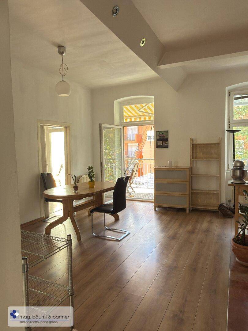 Heller Essbereich mit Holztisch, Stühlen und Zugang zu einem Balkon.