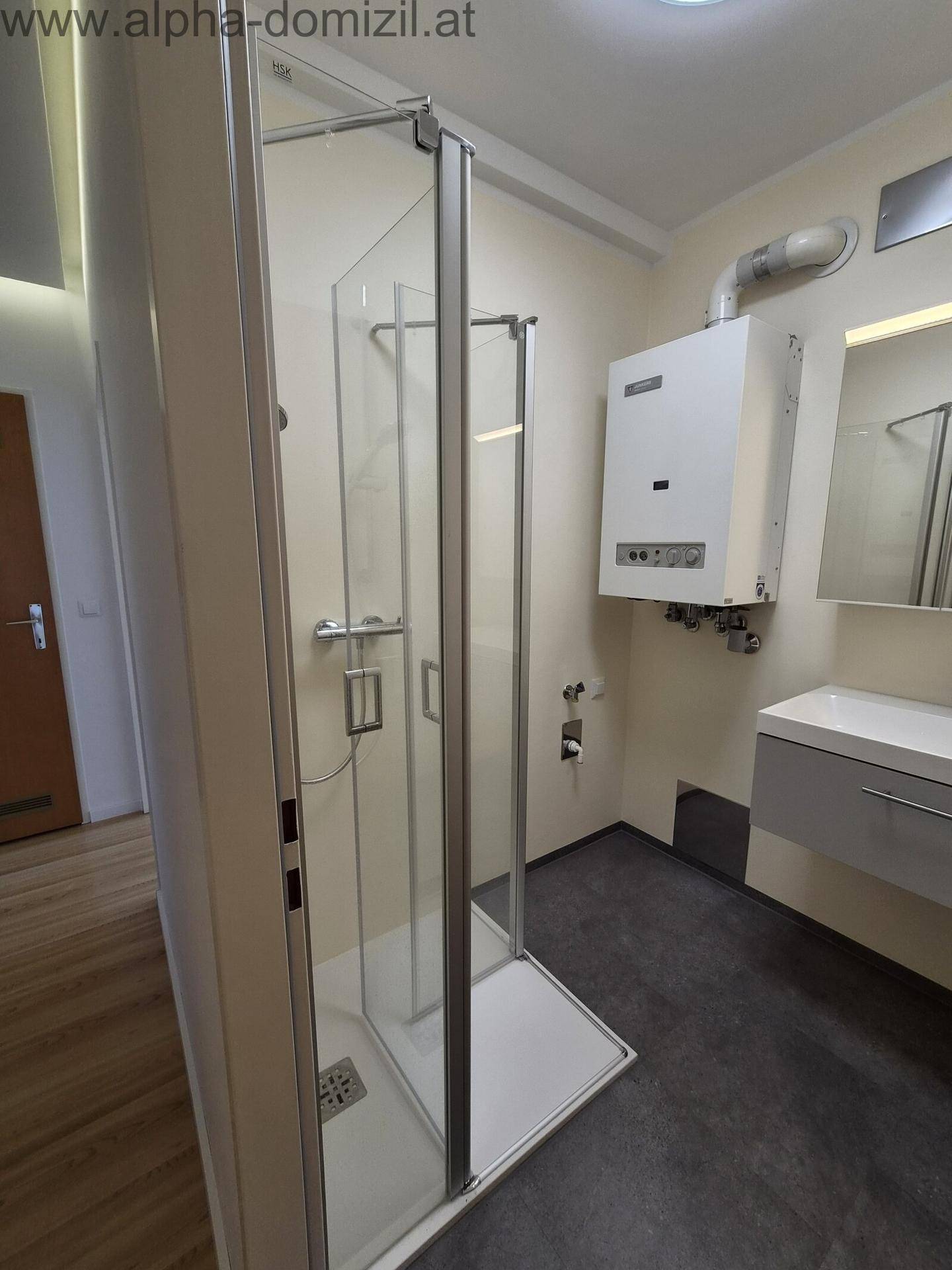 Modernes Badezimmer mit Duschkabine, Waschbecken und Gastherme an der Wand installiert.