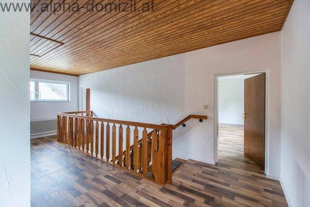 Obergeschoss-Flur mit Holzgeländer, Holzdeckenverkleidung und Laminatboden.