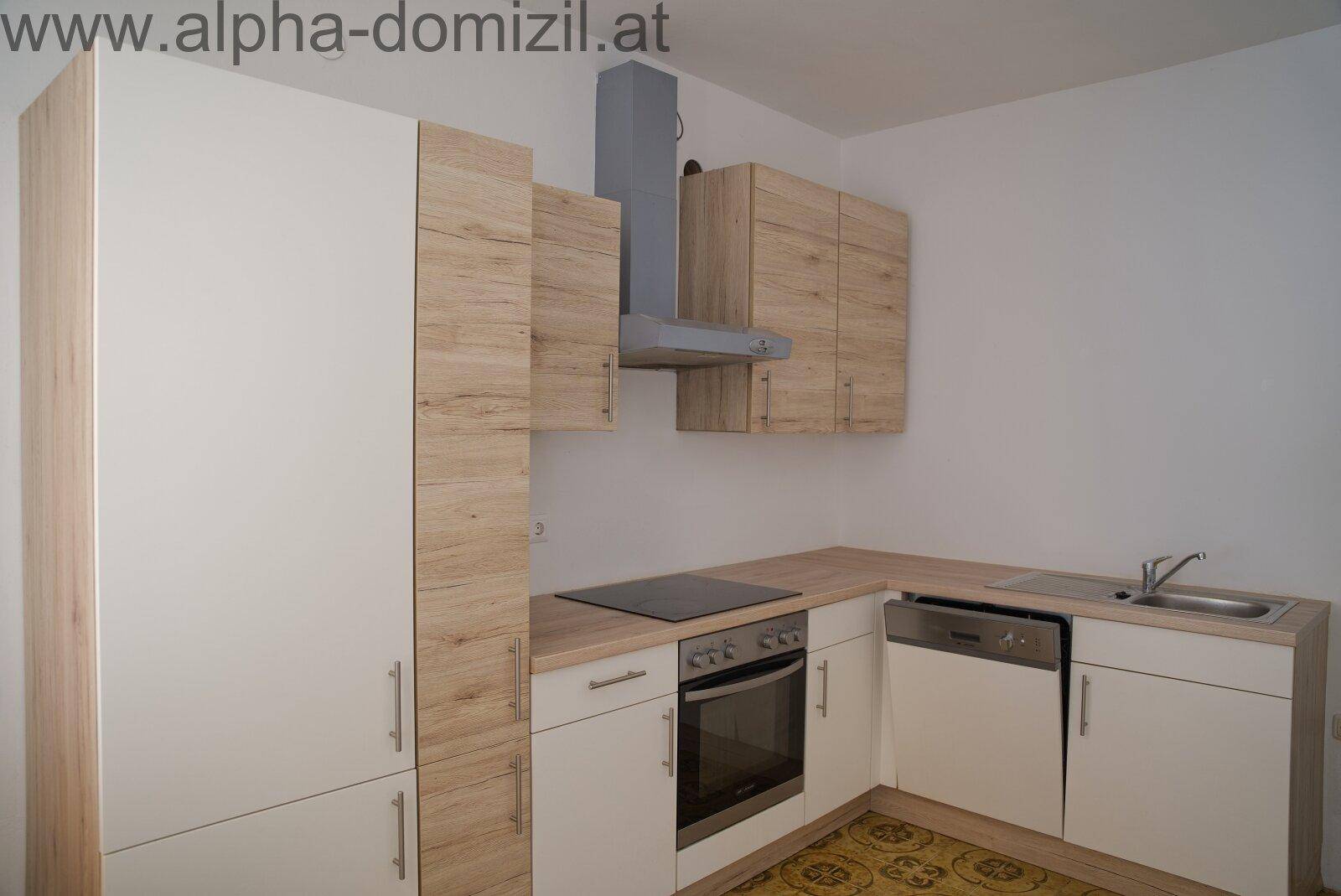 Moderne Einbauküche mit hellen Holz- und weißen Fronten, ausgestattet mit Kochfeld und Backofen.