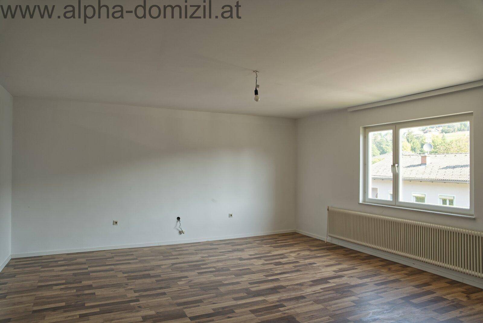 Helles Zimmer mit Laminatboden und Fenster, das eine weite Aussicht bietet.