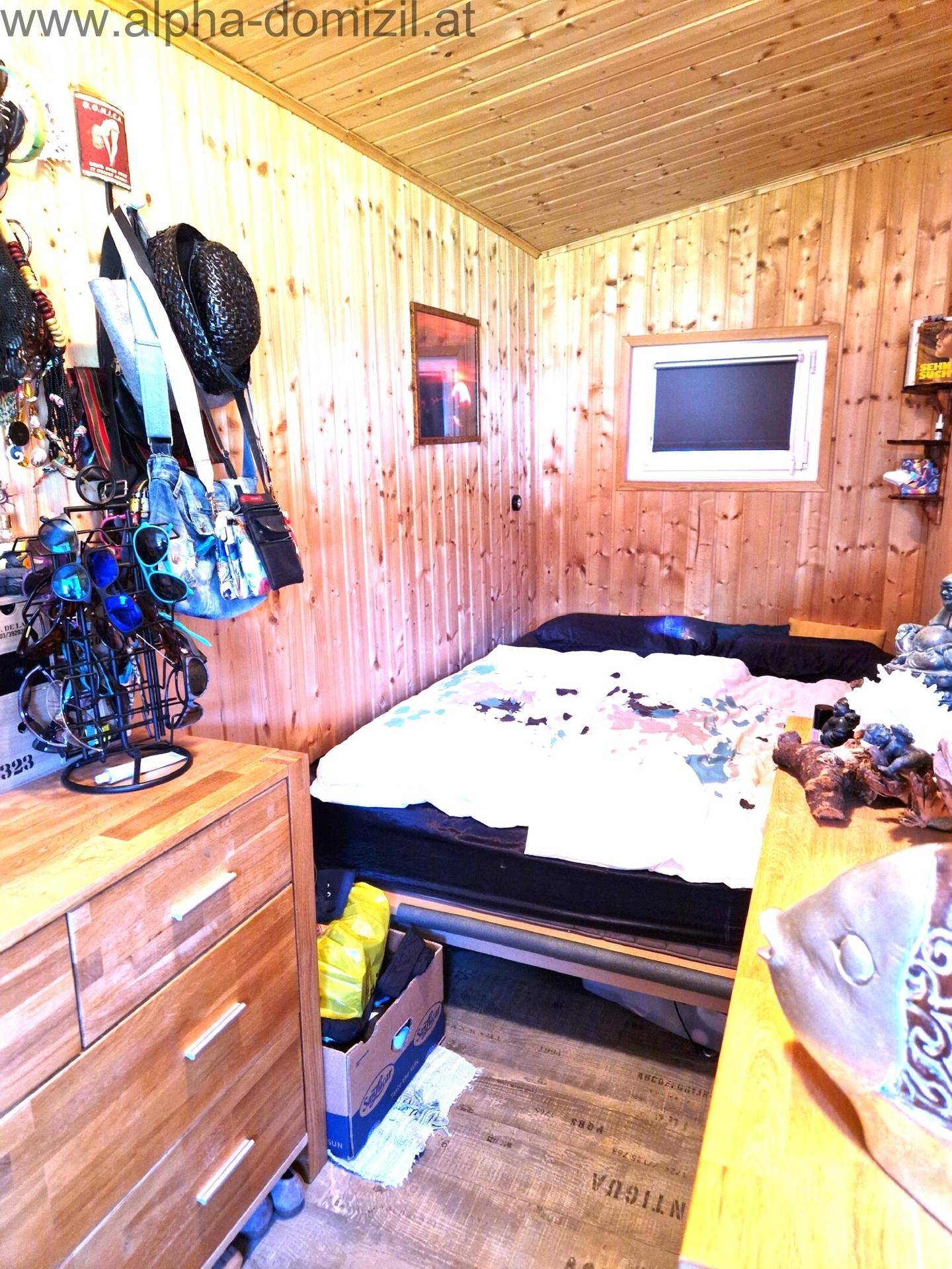 Kleines Schlafzimmer mit rustikaler Holztäfelung an Wänden und Decke, ausgestattet mit einem Einzelbett.