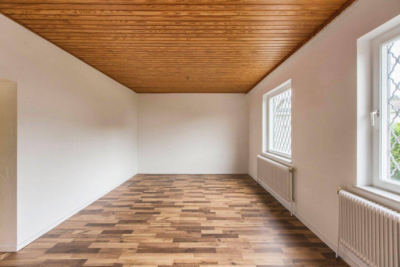 Heller Raum mit Holzboden und einer charakteristischen Holzdecke, die Wärme ausstrahlt.