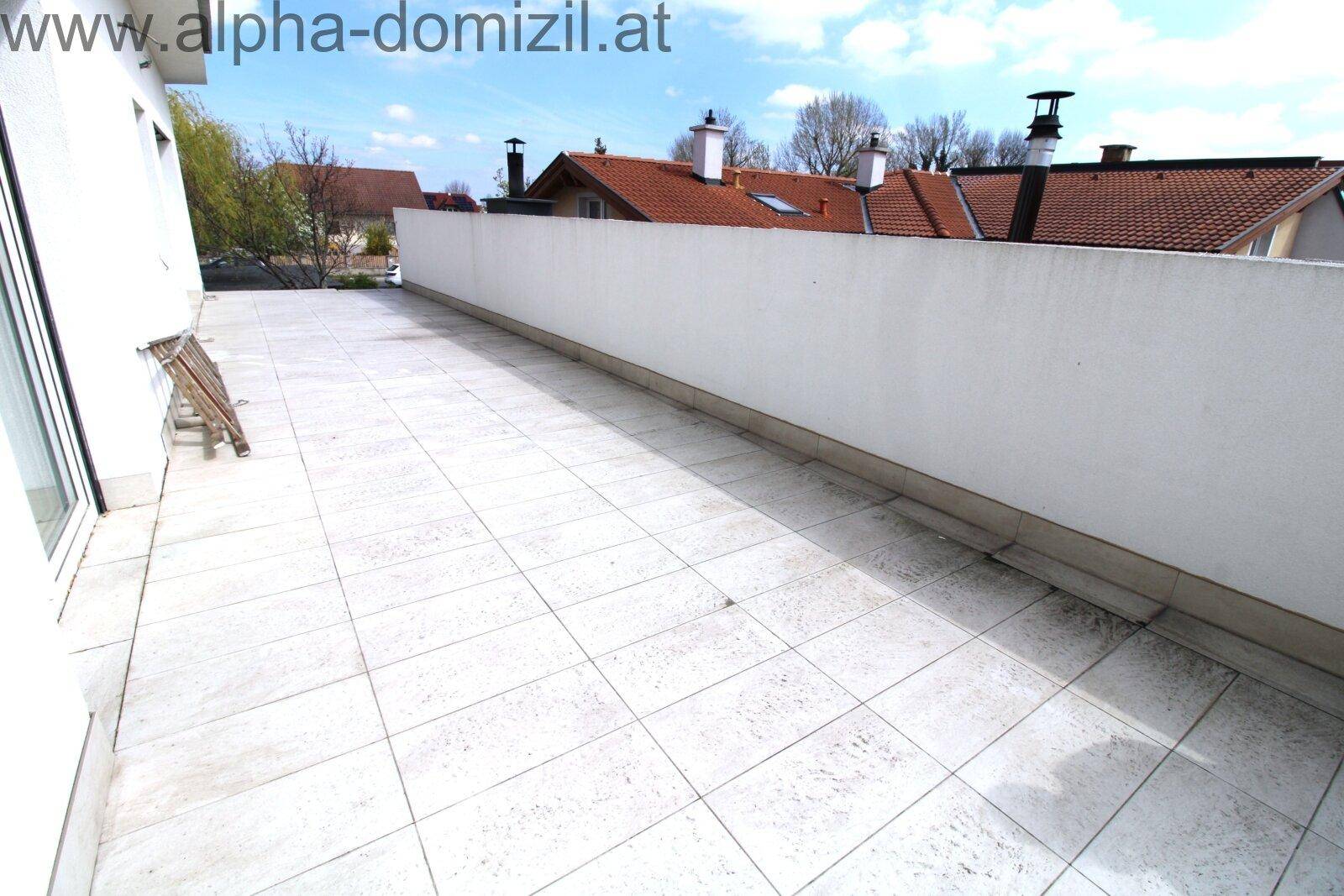 Große geflieste Terrasse mit hoher Mauer, ideal für Entspannung im Freien.