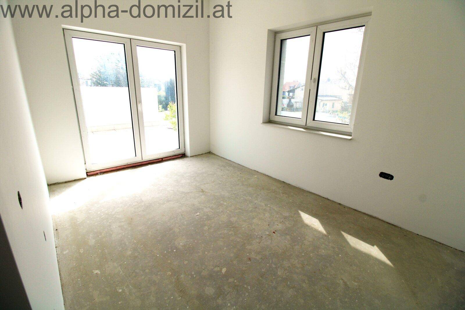Helles, unfertiges Zimmer mit großem Fenster und Zugang nach draußen.