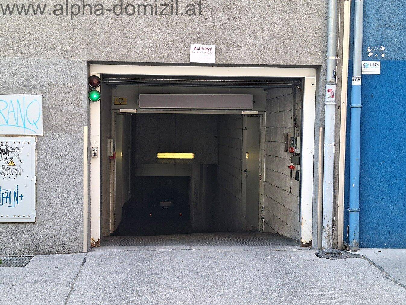 Einfahrt zur Tiefgarage von der Straße aus mit Ampelsignal.