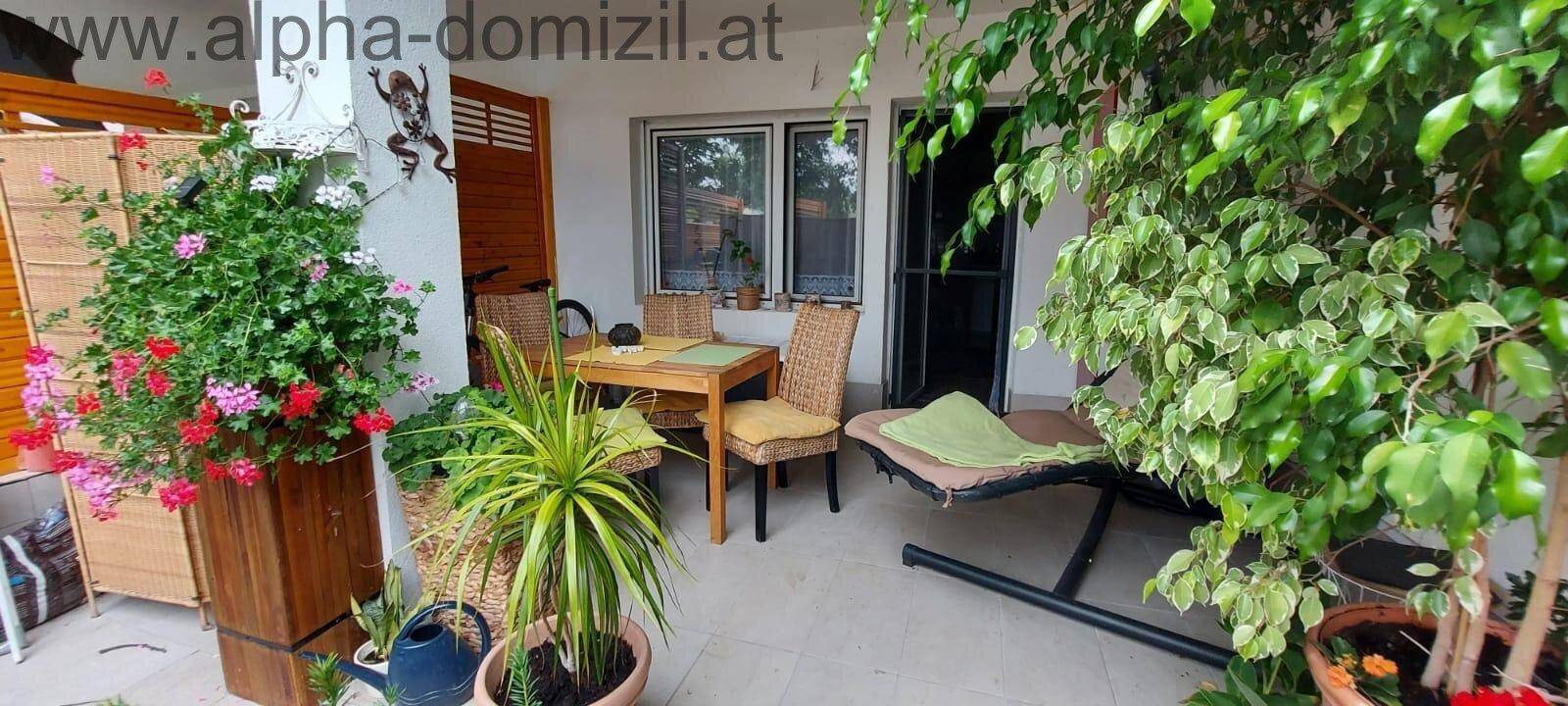 Überdachte Terrasse mit Gartenmöbeln und vielen Pflanzen für entspannte Stunden.