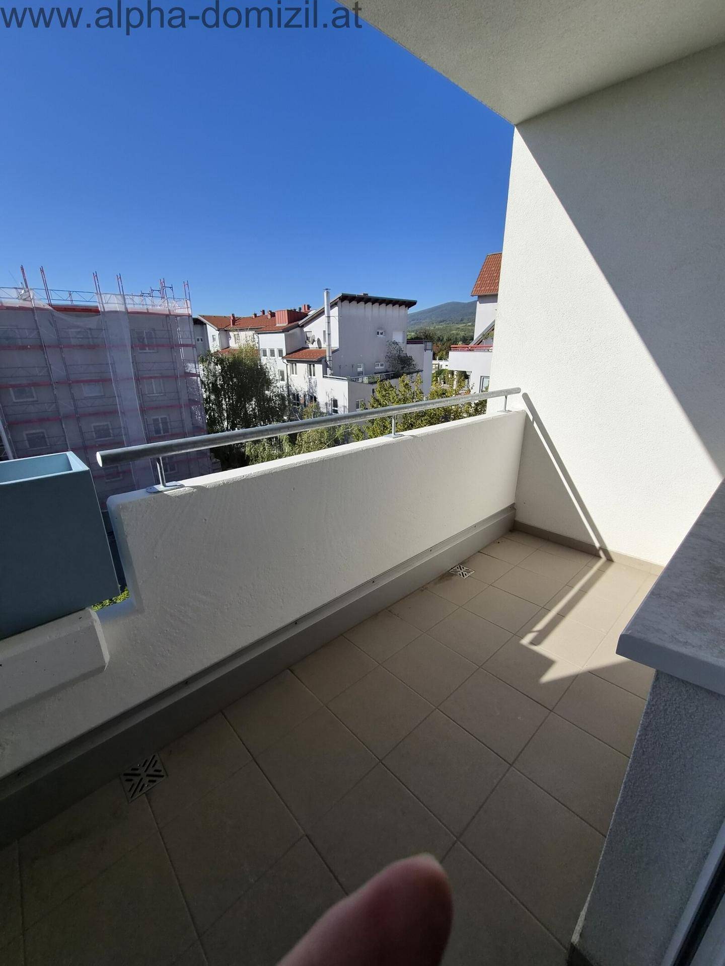 Heller Balkon mit Fliesenboden und Metallgeländer, bietet einen weiten Ausblick an einem sonnigen Tag.