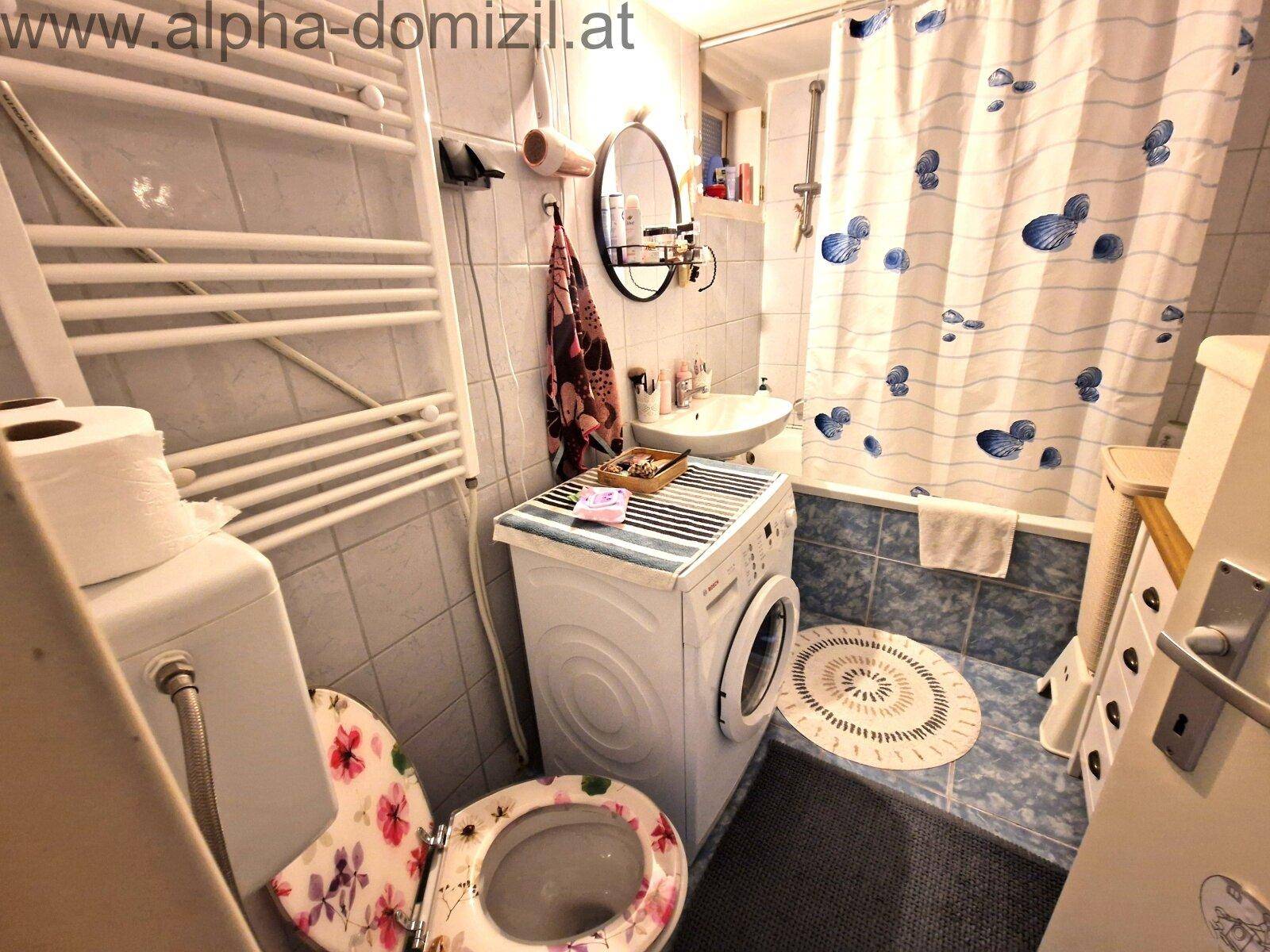 Badezimmer mit Badewanne, Dusche, WC und Waschmaschine in funktionalem Design.
