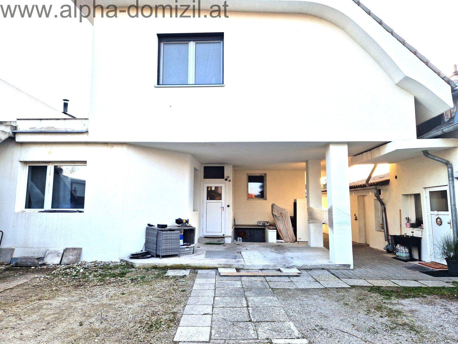 Rückseite des Hauses mit überdachtem Bereich und Zugang zum Garten.