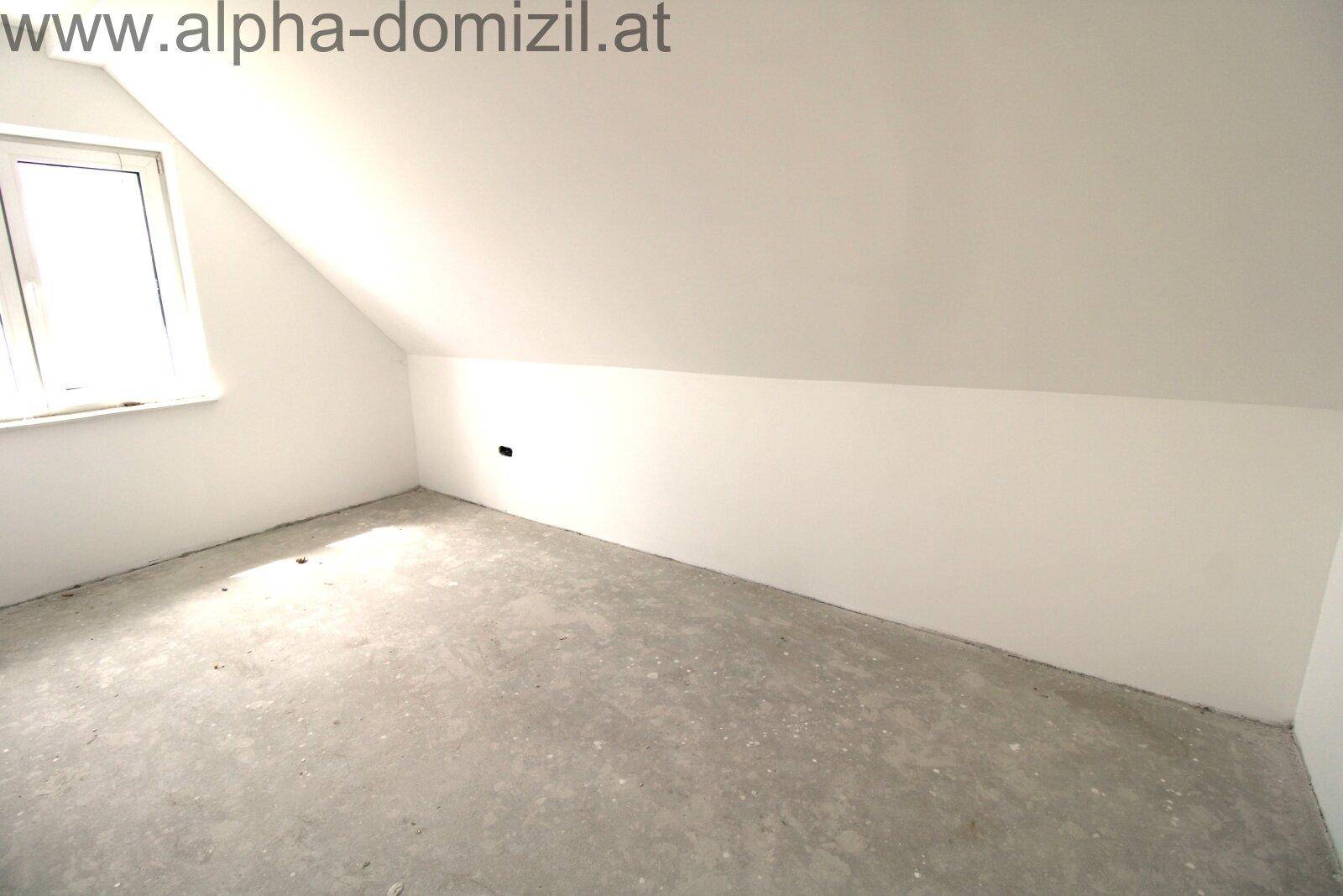 Unfertiges Schlafzimmer im Dachgeschoss mit schräger Decke und Fenster.