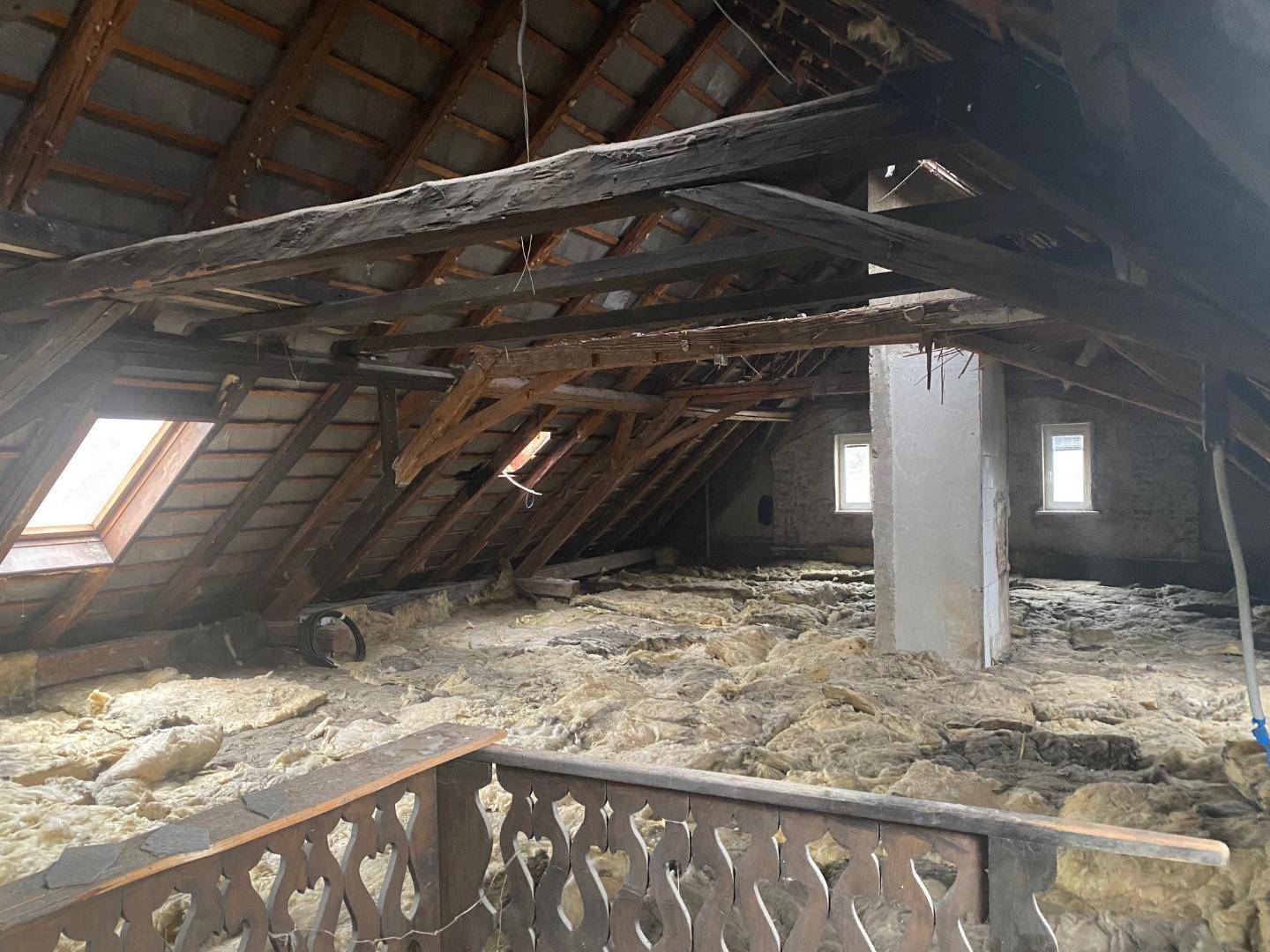 Geräumiger Dachboden mit freiliegenden Holzbalken, Isolierung und Potenzial zum Ausbau des Raumes.