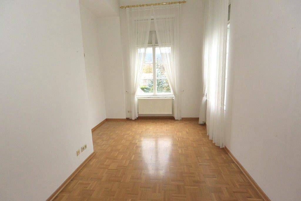 Ruhiges Schlafzimmer mit Parkettboden, weißen Wänden und einem großen Fenster für viel Licht.