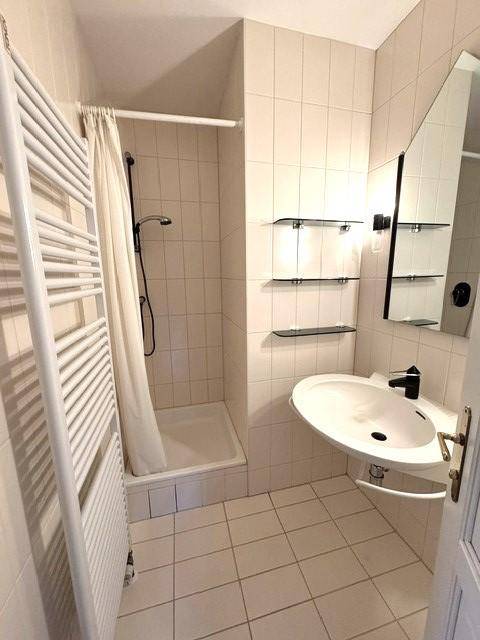 Modernes Badezimmer mit Dusche, Einzelwaschbecken und beheiztem Handtuchhalter.
