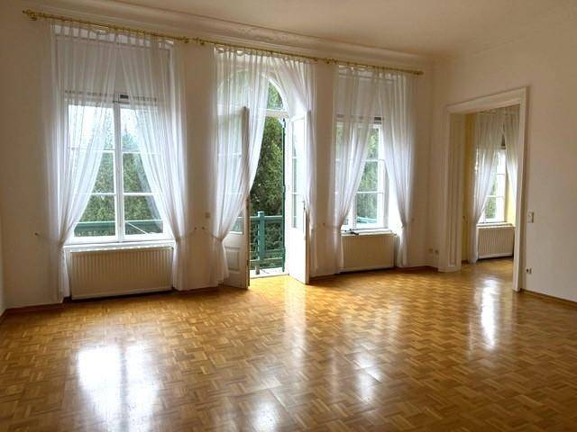 Lichtdurchflutetes Wohnzimmer mit Parkettboden und direktem Zugang zu einem Balkon.