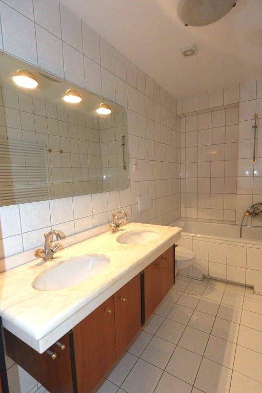 Geräumiges Badezimmer mit Doppelwaschbecken, Marmorplatte und Badewanne, vollständig gefliest.