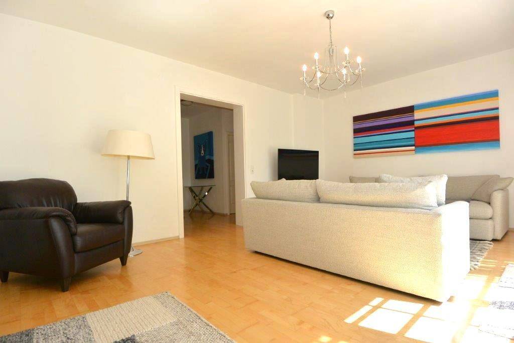Gemütliches Wohnzimmer mit Holzboden, bequemen Sofas und farbenfrohem Wandbild.