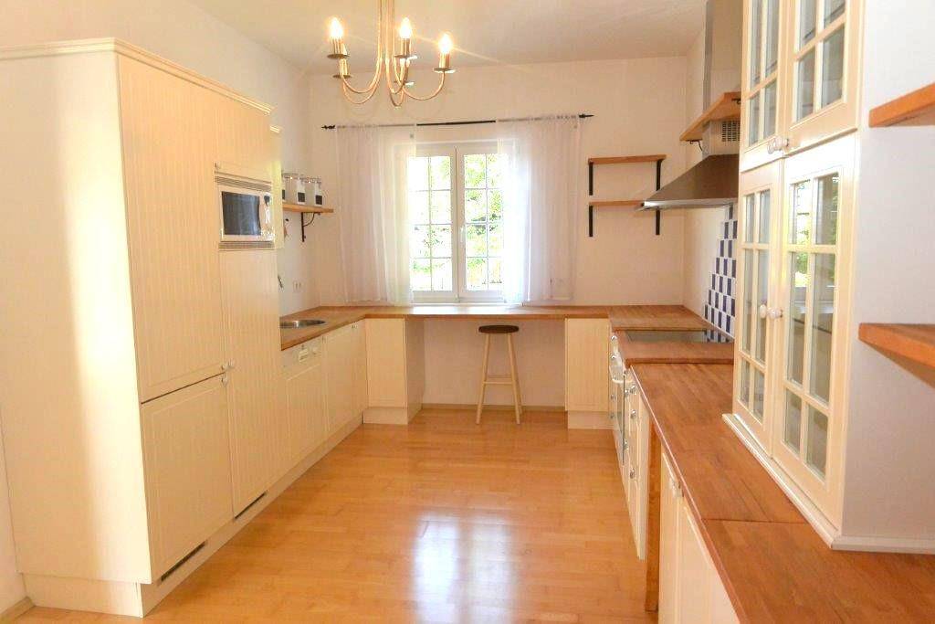 Helle Küche mit Holzboden, weißen Schränken und Arbeitsplatten aus Holz.