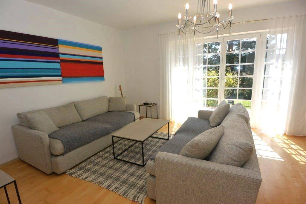 Lichtdurchflutetes Wohnzimmer mit Holzboden, zwei Sofas und Zugang zur Terrasse.