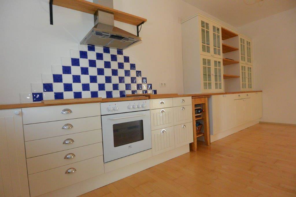 Küchenzeile mit Backofen, Kochfeld und blauen Fliesen als Spritzschutz.