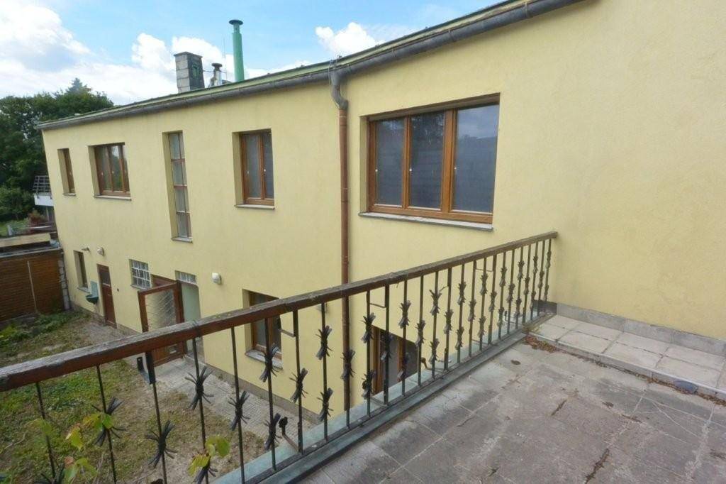 Große Terrasse mit Metallgeländer und Blick auf den unteren Gartenbereich des Hauses.
