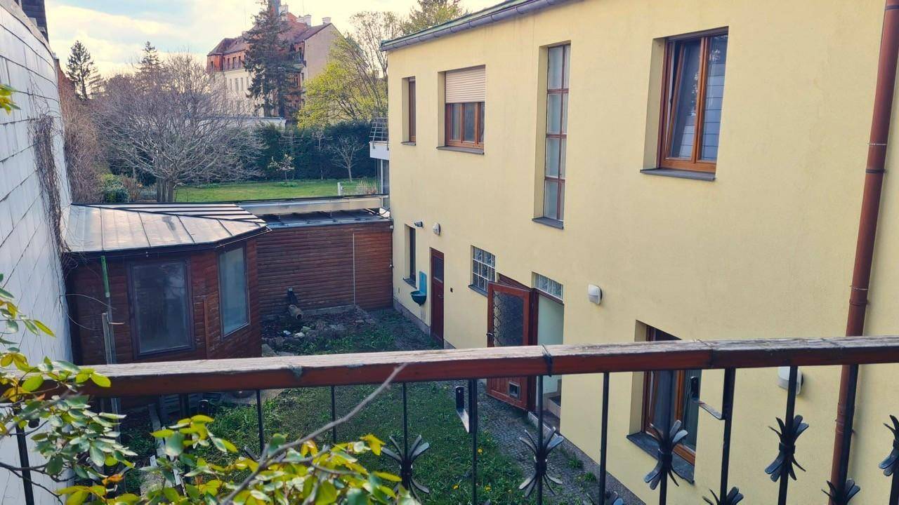 Blick vom Balkon auf den Hinterhof mit kleinem Gartenbereich und einem Nebengebäude.