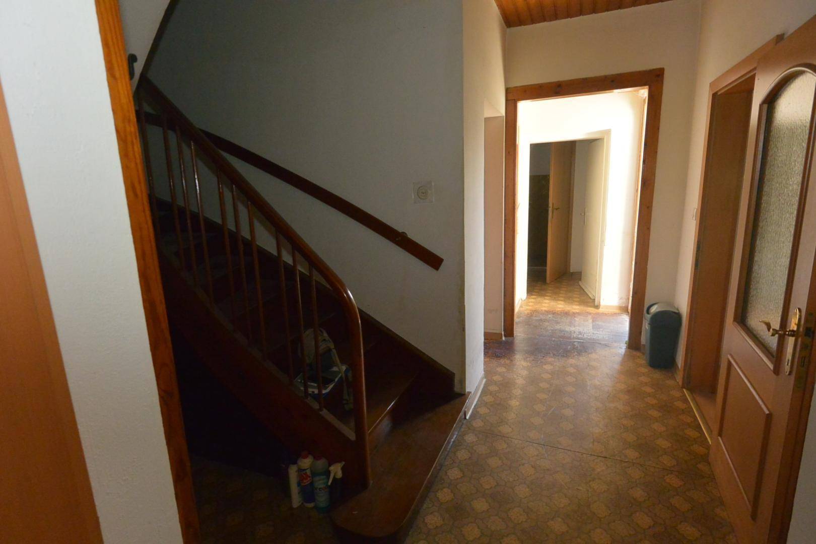 Flur mit Holztreppe und gemustertem Fliesenboden, der zu weiteren Räumen führt.