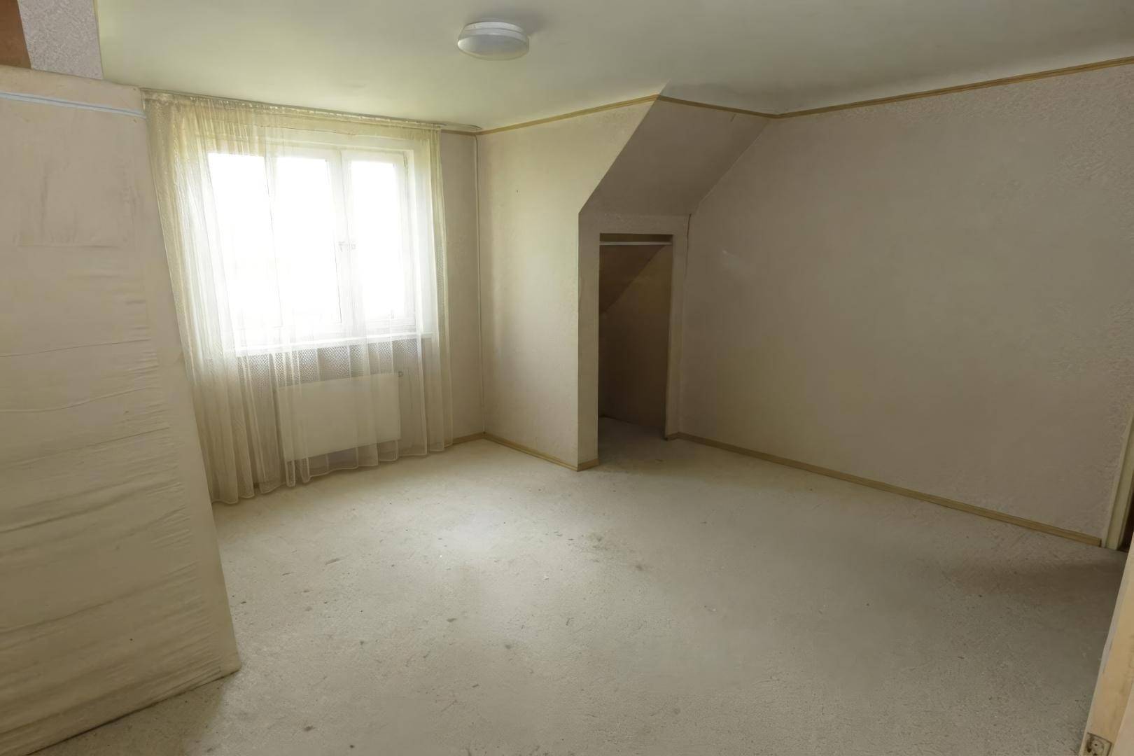 Schlafzimmer im Dachgeschoss mit Teppichboden, Fenster und schrägen Wänden.