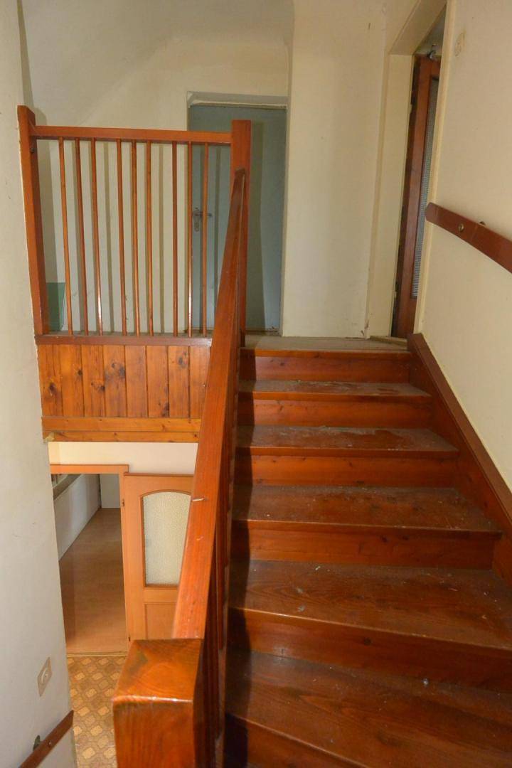 Holztreppe mit Geländer, die in das obere Stockwerk des Hauses führt.