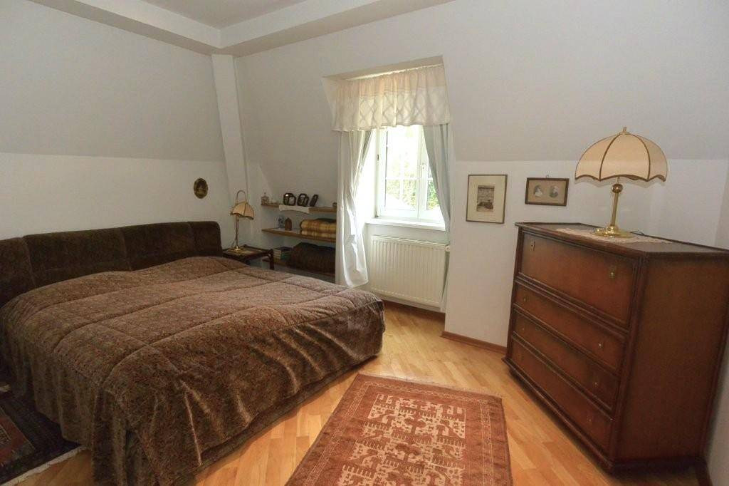 Gemütliches Schlafzimmer mit Doppelbett, Holzkommode und Fenster unter der Dachschräge, strahlt Ruhe aus.