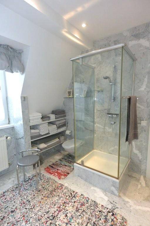 Modernes Badezimmer mit Marmorfliesen, geräumiger Duschkabine und Toilette, unter einer Dachschräge gelegen.