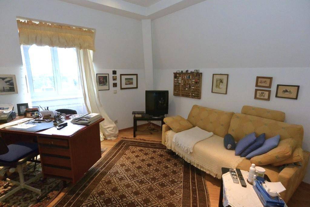 Helles Arbeitszimmer mit Schreibtisch, bequemer Couch und Fenster, ideal für konzentriertes Arbeiten oder Lesen.
