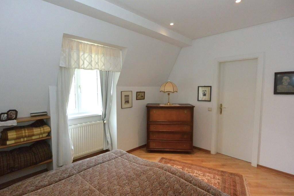 Helles Schlafzimmer mit Doppelbett und klassischer Holzkommode, bietet eine ruhige Atmosphäre unter der Dachschräge.