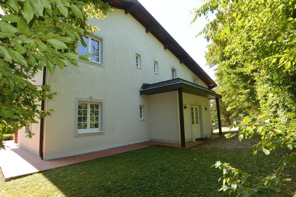 Rückseite des Hauses mit überdachtem Eingangsbereich und gepflegter Grünfläche.