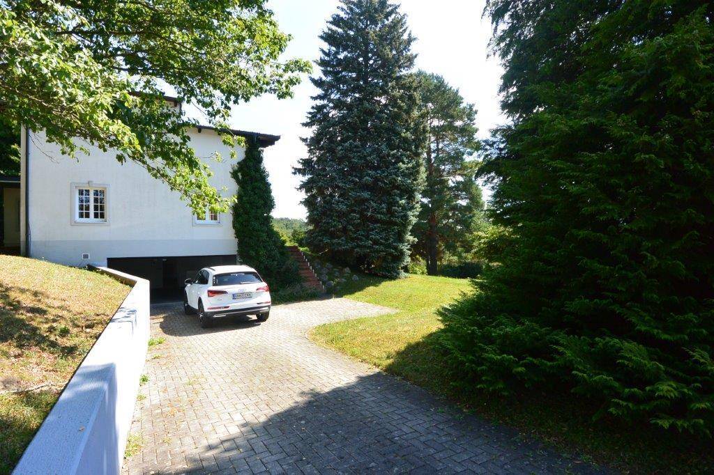 Zufahrt zum Haus mit gepflastertem Bereich und integrierter Garage.