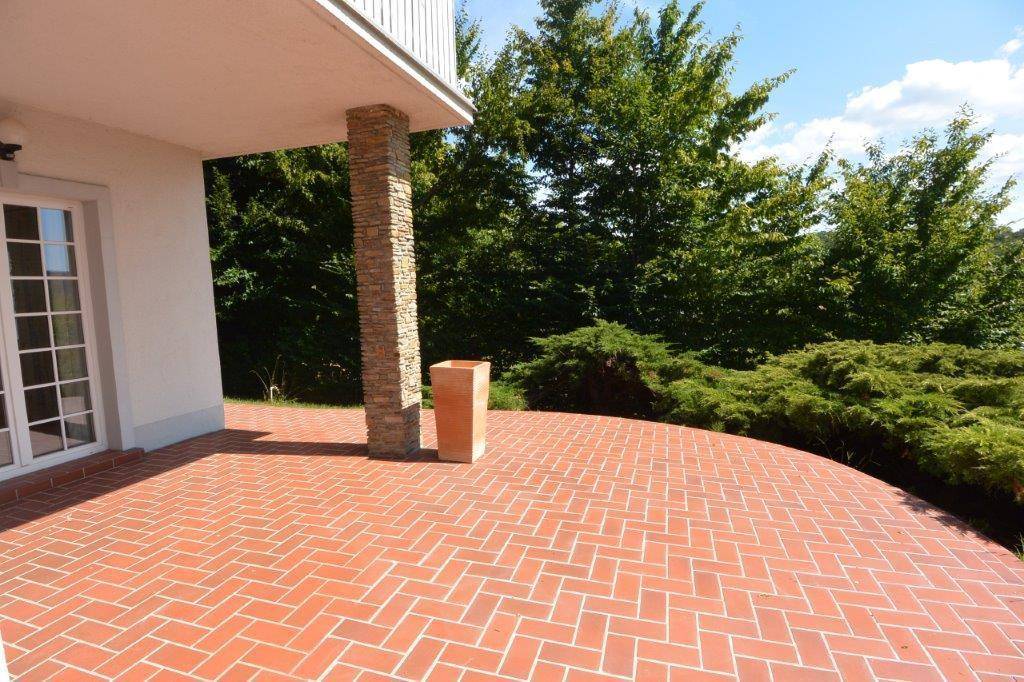 Helle Terrasse mit Ziegelboden und einem dekorativen Steinsäulen-Element.