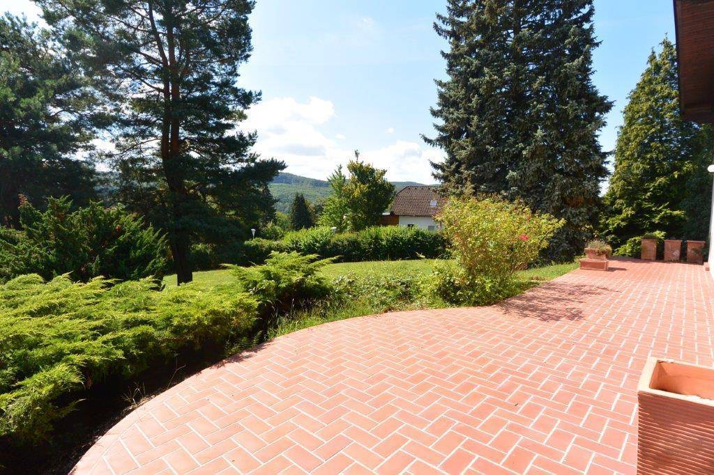 Weitläufige Terrasse mit Ziegelboden und Panoramablick auf die umliegende Natur.
