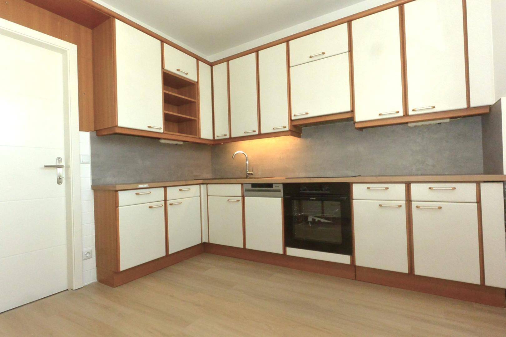 Einbauküche mit weißen Schrankfronten, Spüle, Geschirrspüler und Backofen, funktional eingerichtet.