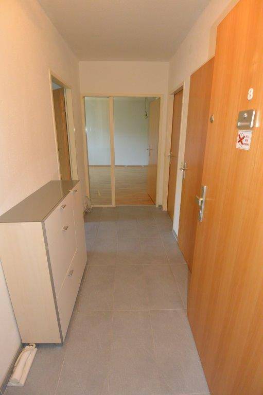 Eingangsbereich mit Fliesenboden und einem praktischen Schuhschrank, der zu verschiedenen Räumen führt.