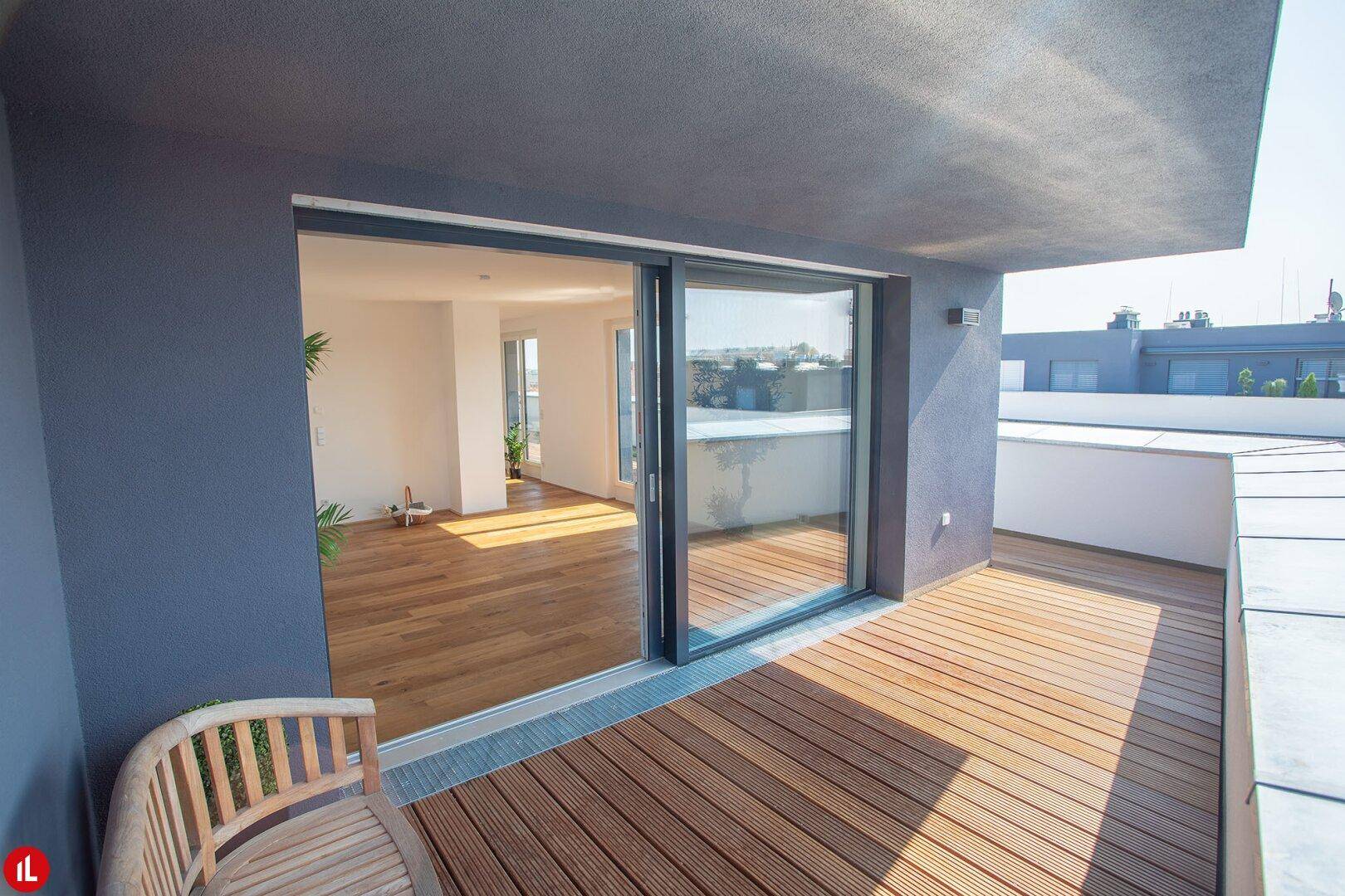 Geräumige Terrasse mit Holzdielen und Schiebetür zum Wohnbereich.