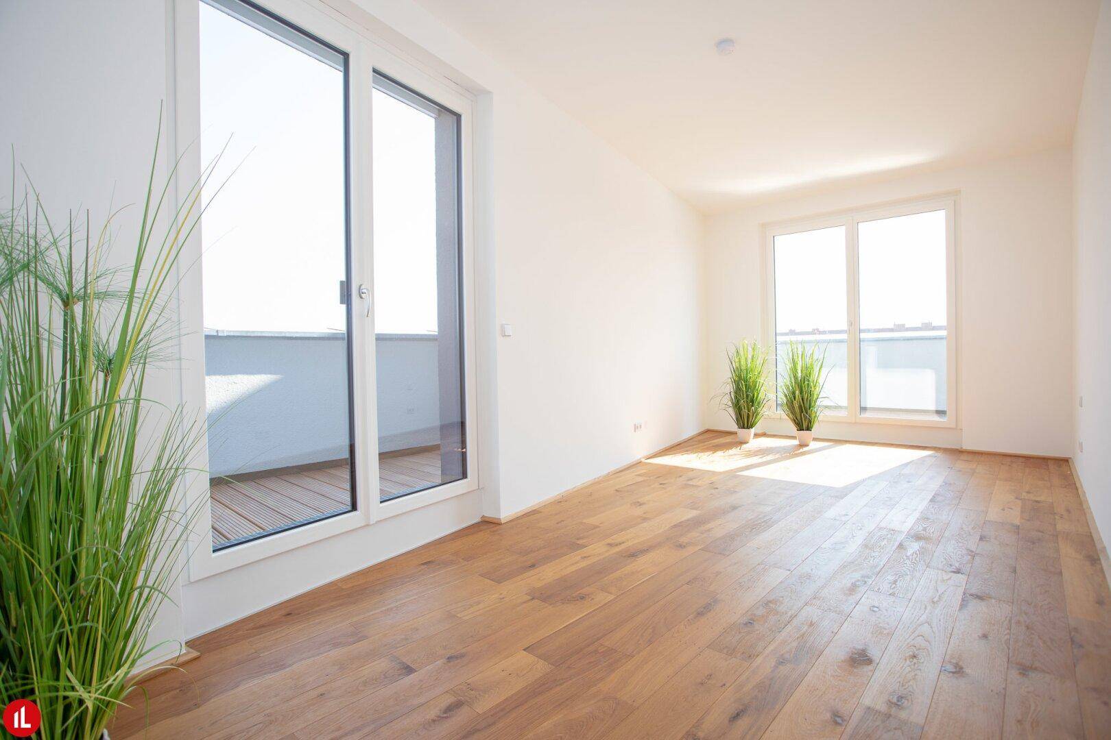 Lichtdurchfluteter Wohnbereich mit Holzboden und großen Fenstern zum Außenbereich.