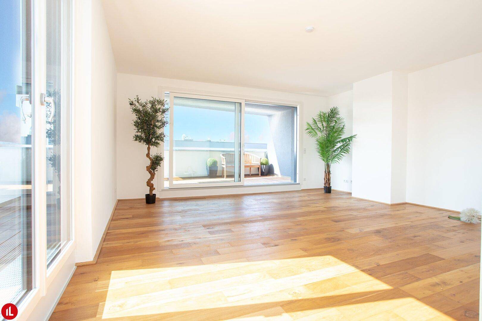 Geräumiges Wohnzimmer mit Holzboden, großen Fenstern und Blick auf die Terrasse.